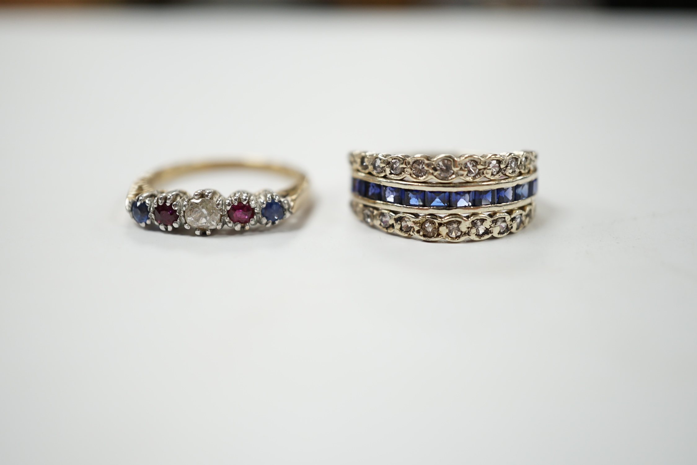 An engraved white metal sapphire ruby and diamond set swivelling triple band ring, size M/N, together with a modern 9ct gold, sapphire, ruby and diamond set five stone half hoop ring, gross weight 5.9 grams. Condition -